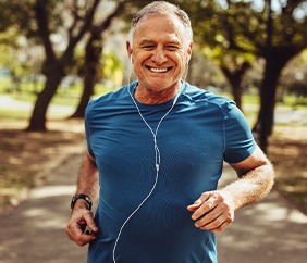 Senior man smiling while jogging outside