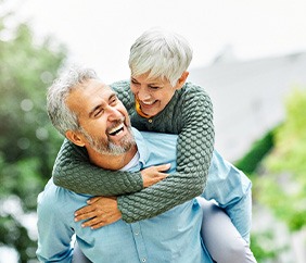 Senior couple smiling while hugging outside