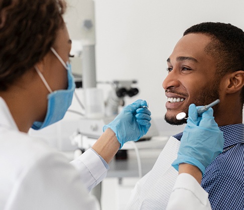 Dentist using dental tools to examine patient's teeth