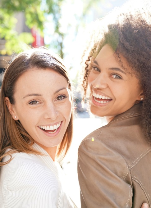 Two women sharing beautiful smiles after cosmetic dentistry