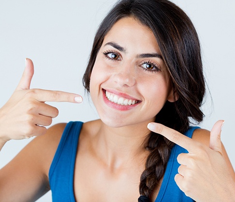 woman smiling and pointing at dental crowns in Mankato
