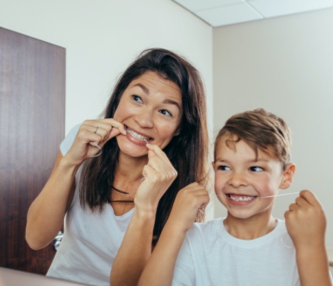 Mother and child flossing teeth together to prevent dental emergencies