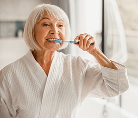 woman brushing her teeth in a bathroom mirror