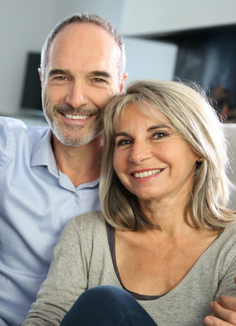 Man and woman smiling after replacing missing teeth