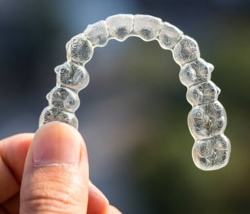 Hand holding a clear aligner tray