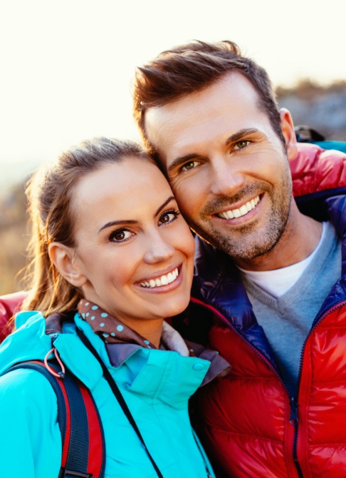 Man and woman smiling outdoors after preventive dentistry visit