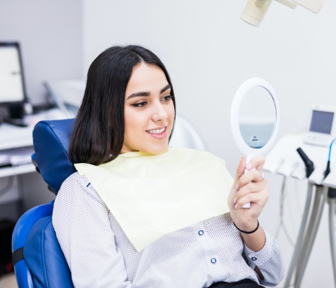 Woman looking at her smile during dental checkup and teeth cleaning visit