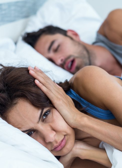 Frustrated woman next to snoring man in need of sleep apnea therapy