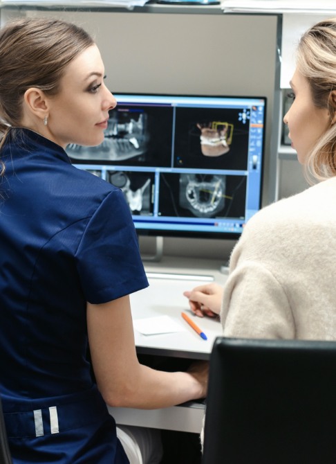 Two dental team members reviewing digital dental x-rays on computer screen