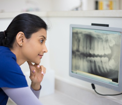 Dental team member reviewing digital x-rays of patient's smile