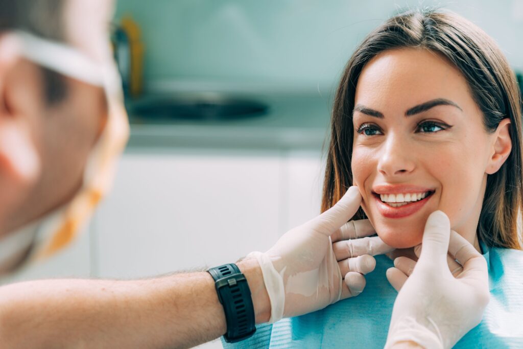 Woman smiling as dentist touches her cheeks with gloved hands