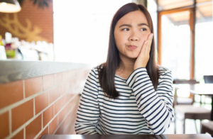 Woman rubbing her jaw and looking off to the side with a questioning expression